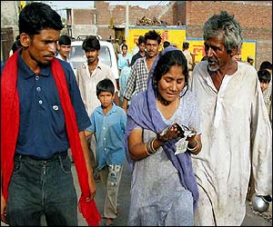 Woman cries as she looks at a newspaper picture of her dead son while others look on