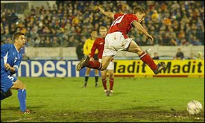 Michael Owen tries in vain to nod in David Beckham's goal-bound free-kick