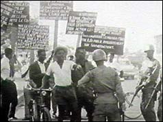 Protesters with placards confronted by army officer