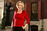 Lucy Worsley stands outside a historic home