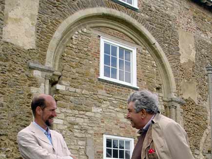 Martin Palmer (left) with Prof Jonathan Riley-Smith in front of the grey stone and brick building of Denny Abbey. Gaps and repairs are visible all over the wall