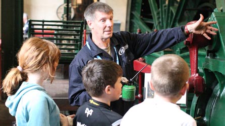 Man telling children about the Victorian winding engine at the Winding Museum, New Tredegar