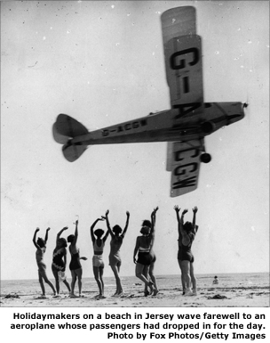 Holidaymakers on a beach in Jersey wave farewell to an aeroplane whose passengers had dropped in for the day. (Photo by Fox Photos/Getty Images)