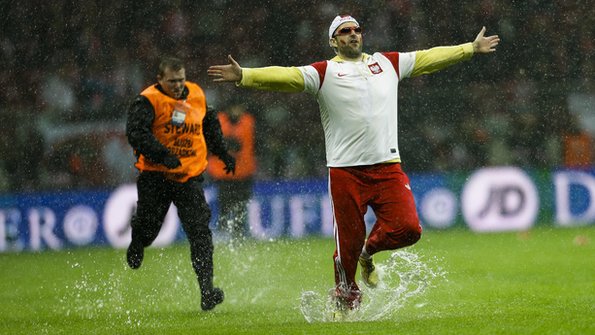A Poland fan is chased by a steward as he invades the pitch