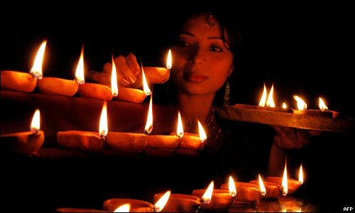 A woman lighting clay lamps for Diwali