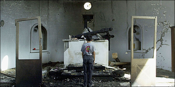 A man standing in front of the altar of a burne out church