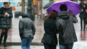 Rainy street scene featuring people with umbrellas