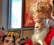 The Coptic Orthodox Pope Shenouda III, bearded gentleman in red and gold robe, with head bowed as if in prayer