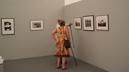 People examining photographs in the Lle Celf (Art space).