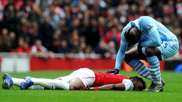 Mario Balotelli reaches towards the injured Bacary Sagna