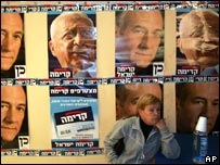 Simpatizante do Kadima em frente a cartazes do premiê Ehud Olmert e de Ariel Sharon