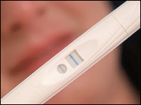 woman looks at positive pregnancy test