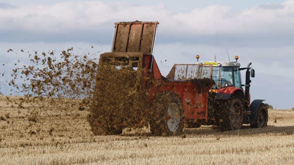 Tractor and muckspreader driving across a field