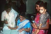 Woman holding a child registers with medical staff