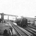 Train on LMS line passes under LNER viaduct, signal box -right
