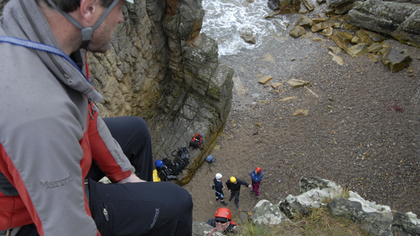 Ian Cockran rock climbs to the top of the cliff, while Instructor Al Gilmore attends to the ropes.