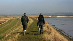 A man and a woman walk 'briskly' by a river