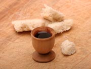 Broken loaf of bread and wine in a wooden cup