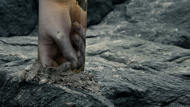 A reconstruction of a lifeless human hand inside a jar full of pale yellow fluid.