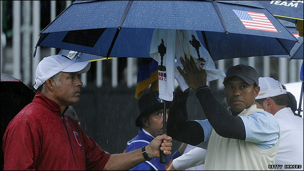 Tiger Woods (right) and caddie Steve Williams take some welcome shelter as the American third pairing await to tee off on the first hole