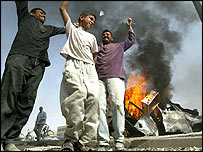 Mladí Iráčané tančí kolem hořících aut ve Fallúdži