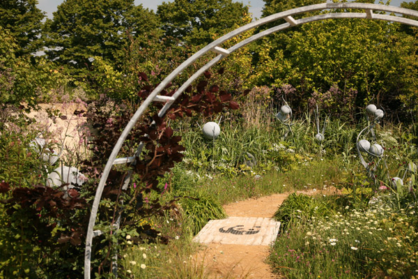 A gateway framed with copper beech leads into the Why We Care About Chalk Streams garden, Hampton Court Palace Flower Show 2011
