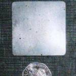 Piece of flak jacket from Little Boy Blue sized against a 50p coin