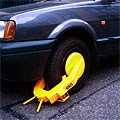 A yellow wheel-clamp fixed on a car's front wheel