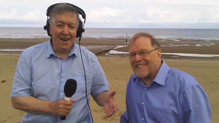 Hywel Gwynfryn a Gareth Owen, cyfarwyddwr Pafiliwn Rhyl, ar draeth y Rhyl