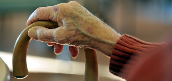 An elderly person's hand on a walking stick