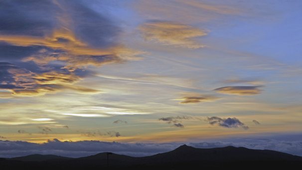 Blue sky and uplit clouds as the sun sets over Bennachie
