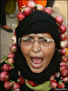 Indian woman wearing a garland made with onions during a protest against the price rise