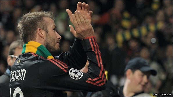Beckham puts a green and gold scarf around his neck