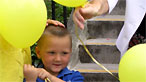 Child with balloon holding parent's hand
