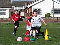 Boys dribbling ball around cones