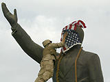 US Marine covering the face of the statue of Saddam Hussein with the US flag in al-Fardous square.