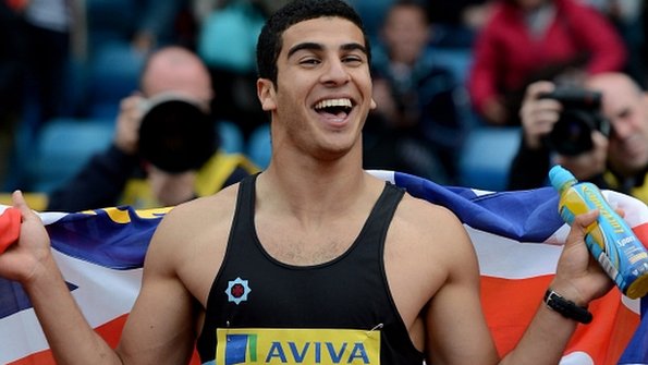 Adam Gemili drapes the British flag round his shoulders after securing an Olympic spot by finishing second in the 100m.