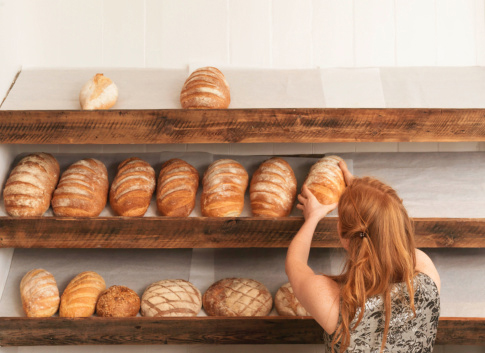 Woman arranging bread in artisanal bread shop