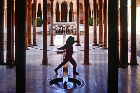 Child jumping over a fountain, photo by Tom Ang