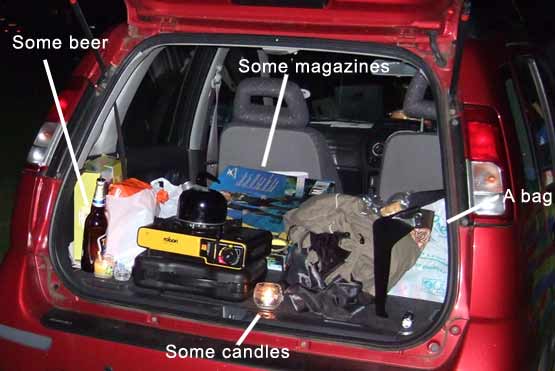 A car boot packed with things, including some beer, some magazines, some candles and a bag