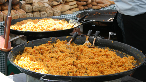 Large pans of rice being cooked at a market