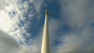 Low-angle view of wind turbine against a blue sky.