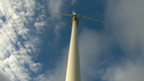 Low-angle view of wind turbine against a blue sky.