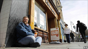 A man begs for money outside a branch of the EBS building society in central Dublin, Ireland