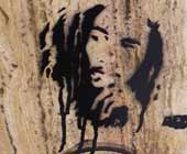 Spray-painted stencil on a wall in a likeness of Bob Marley.