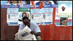 A man reading a newspaper below campaign posters in khartoum