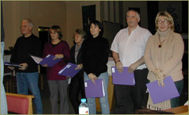 John and others listen to their colleagues sing