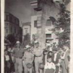 3599121 William Leslie Renney (in centre of photograph wearing a civilian hat) with some of his mates and local children. The photograph may have been taken in Tunisia and the children 'French colonials'.