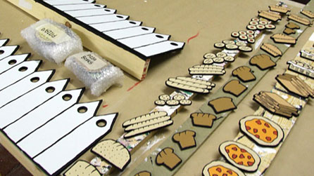 Pieces of scenery including bread, cakes, loaves, pizzas and pizza boxes