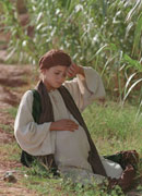 Actress as Mary, a heavily pregnant young girl, sitting exhausted on the roadside